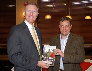 Jerry Stidham (l), chapter president, presents Morgan with a chapter coin and a book at the July luncheon.